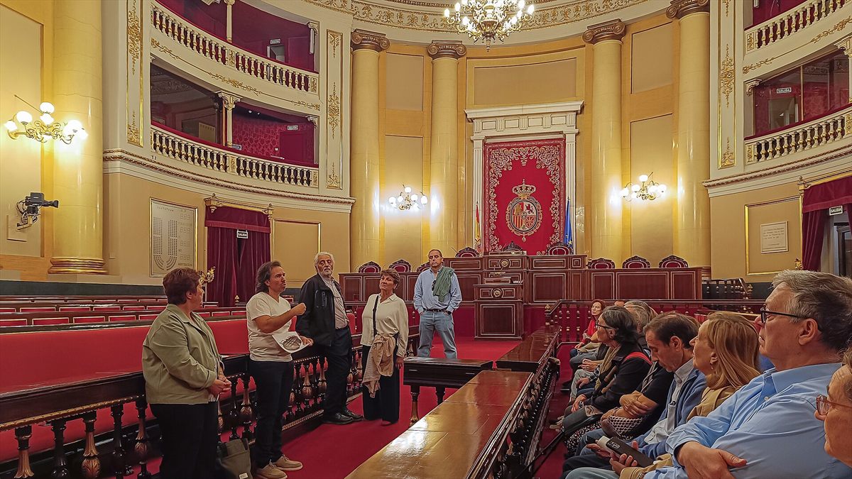 Salón de sesiones del Palacio del Senado, con los escaños, las tribunas y el testero presidido por el tapiz del escudo